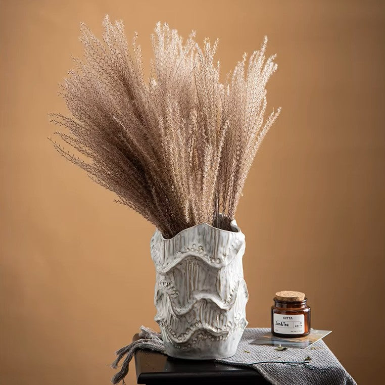 Decorative vase with dried grasses and a jar on a brown background